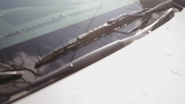 A White Vehicle Under The Heat Of The Sun, Checking If The Windshield And Wipers Are Clean - Close Up Shot