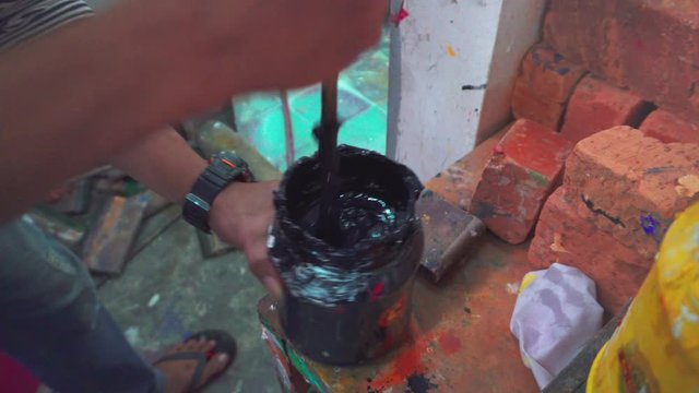 Worker hand mixing ink paint for silk screen printing use at Garment Manufacturers.