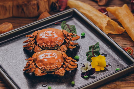 A pair of cooked crabs on a square plate, delicious meat to eat.