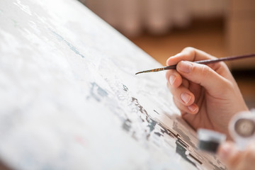 Close up view of artist hand with thin brush drawing a picture