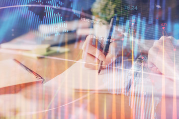 Financial forex graph drawn over hands taking notes background. Concept of research. Multi exposure