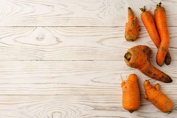 Ugly carrots on a light wooden table.