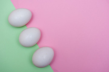 Easter holiday flat lay with white egg on a solid light green pastel background with copy space.