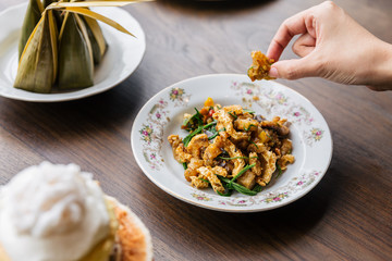 Hand pinching Stir Fried Spicy Crispy Pork Skin with Acaci. Classic Thai cuisine.