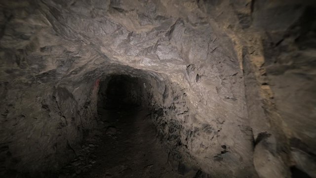 Speleology artificial cave dark tunnel excavation underground. Old adit for the extraction of metal and rocks