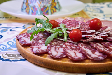 Slicing smoked sausage with cherry tomatoes on a wooden board
