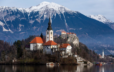 Bled, Slovenia - Panoramic view of the island in Bled lake with Church of the Assumption of Maria, traditional Pletna boats at winter background