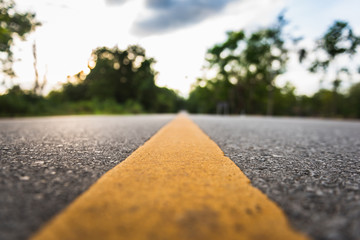 asphalt road with yellow diving line and forest background