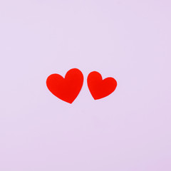 Two red hearts symbolizing a man and a woman on a soft pink background.