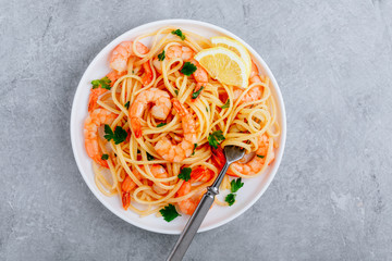 Seafood Pasta spaghetti with shrimps and parsley on gray stone background.