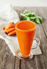 Delicious and fresh carrot juice with mint and lettuce leaves. Chilled vegetable smoothie with ice in a glass glass. Close up