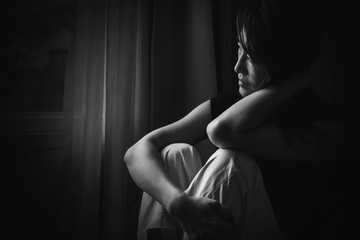 depress woman sitting on chair in room near window in white tone, sadness and depress concept