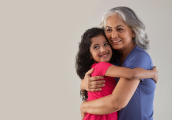 Portrait of a happy grandmother hugging her grand-daughter.  	