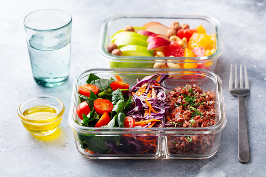 Lunch box with vegetables, brown rice and fruits salad. Healthy eating. Grey background.