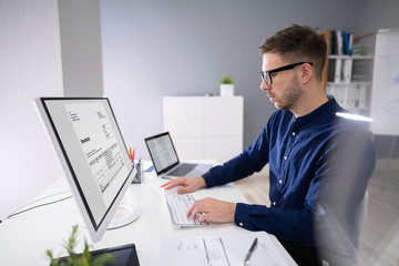 Businessman Calculating Invoice In Office