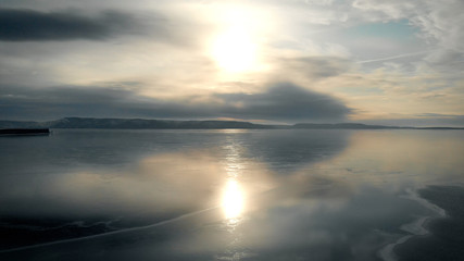 It's an aerial view. The winter landscape of the freezing river. The ice reflects the sky and the sun. Cold temperature.