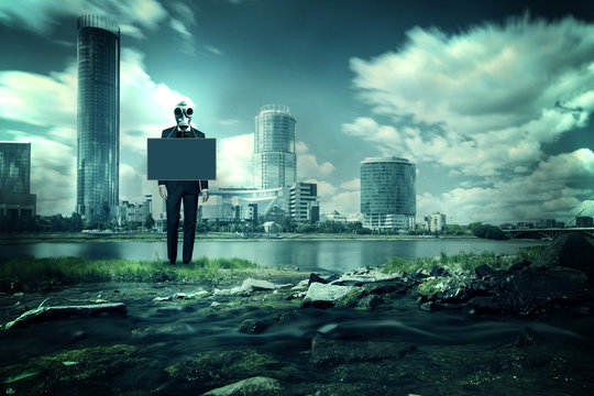 Concept - a man in a business suit and gas mask stands in background of city. He has a placard around his neck with a place for text. Theme of environmental pollution, nature protection, dirty city