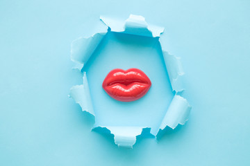 Burst hole female plastic lips abstract on blue background.