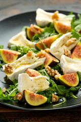 Vegetarian camembert cheese, fig and Arugula, hot rocket salad served on black plate