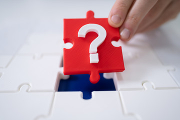 Person Placing Question Mark Piece Into Jigsaw Puzzle