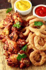 Sticky glazed chicken wings and deep fried battered onion rings served with lemon wedges, tomato ketchup and mustard. Greasy, fast food concept
