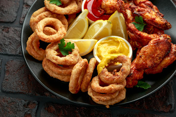 Sticky glazed chicken wings and deep fried battered onion rings served with lemon wedges, tomato ketchup and mustard. Greasy, fast food concept
