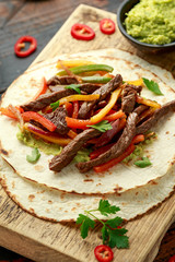Beef Steak Fajitas with tortilla mix pepper, onion and avocado on wooden board