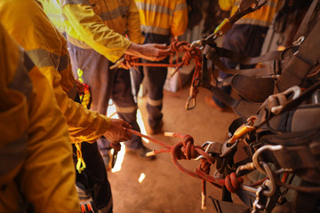 Fototapeta na wymiar Industrial rope access technician inspector double checking inspecting figure of eight knot 10.5 mm static rope call as cawtails after tie into abseiling safety harness loop prior working of each task