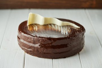 Dark chocolate vegan cake with candies and nuts on wooden background