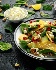 Persimmon, avocado salad with spinach, feta cheese, walnuts and pomegranate seeds. Healthy food.
