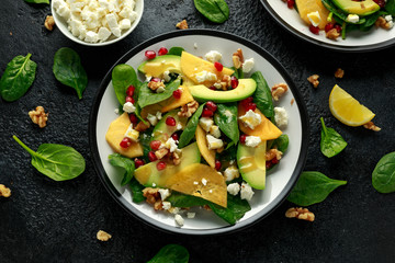 Persimmon, avocado salad with spinach, feta cheese, walnuts and pomegranate seeds. Healthy food.