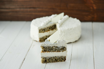Birthday cake with white chocolate, butter cream and poppy seed biscuit on wooden background