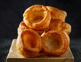 Traditional English Yorkshire pudding side dish on black plate and background