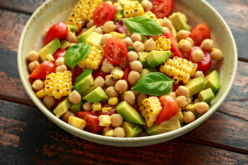 Avocado chickpea salad with grilled sweet corn, tomato and basil. Healthy vegan food