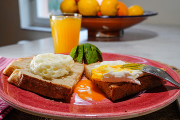 A poached egg on toast with avocado and a glass of juice.