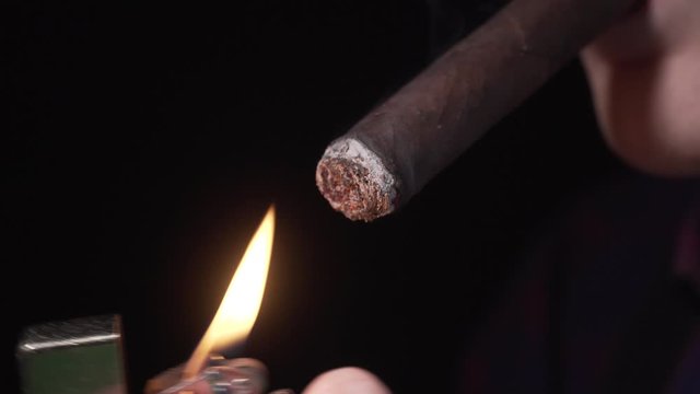 The guy lights a cigar with a lighter. Close-up. 4K