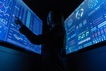 The businesswoman standing near the blue monitor