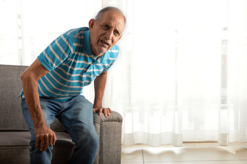 Senior man trying to stand up with a knee pain. (Health and fitness)  