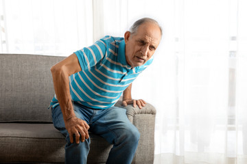 Senior man trying to stand up with a knee pain. (Health and fitness)  