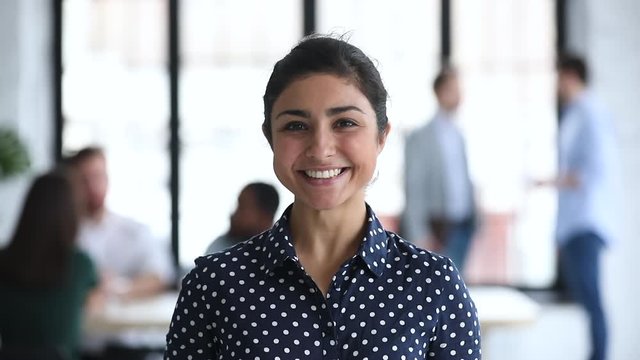 Smiling confident young indian businesswoman looking at camera in office