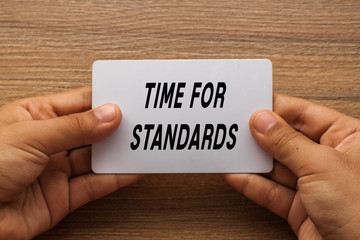 Time for standard written on white card holding with two hands