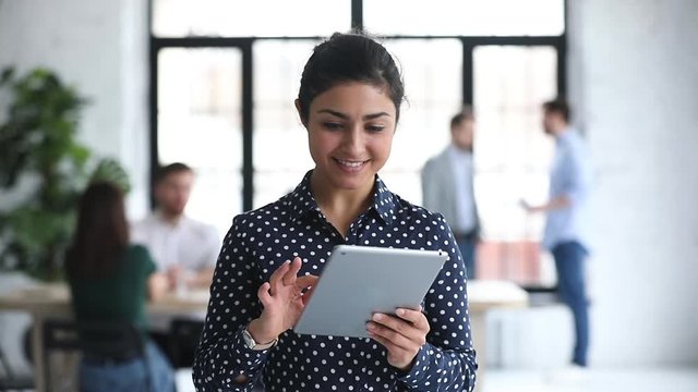 Indian professional businesswoman using digital tablet standing in office