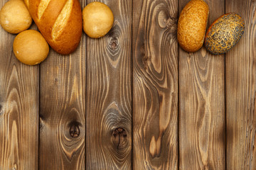 Loaf of bread, buns on a wooden background