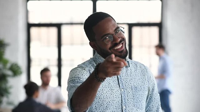 Smiling african ethnic businessman employer pointing finger looking at camera