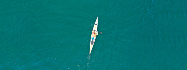 Aerial drone ultra wide photo of fit athletes practising sport kayak in tropical exotic lake with emerald water