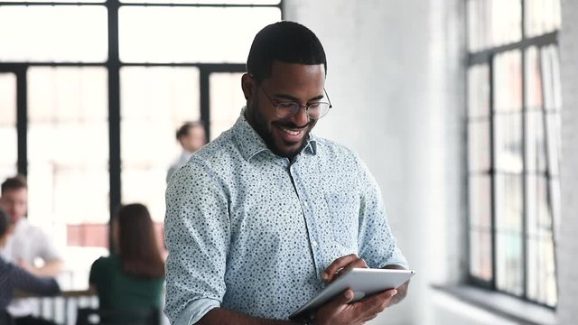 African professional businessman using digital tablet standing in office