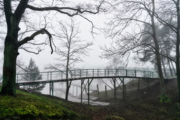 Thick dense fog with poor visibility on a cold winter morning. Historic bridge in the background. Beautiful man-made landscape.