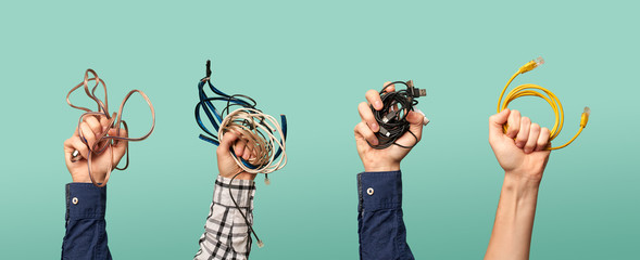 Four hands with some old wires. Concept of electrical waste.