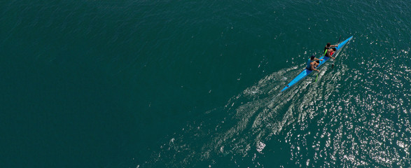 Aerial drone ultra wide photo of fit athletes practising sport kayak in tropical exotic lake with...