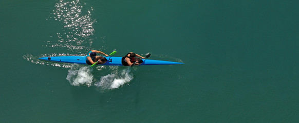 Aerial drone ultra wide photo of fit athletes practising sport kayak in tropical exotic lake with...